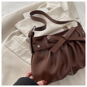 Detailed macro shot of brown pleated leather shoulder bag with bow and star studs