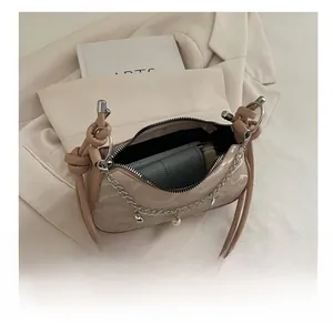 Detail view of beige leather shoulder bag showing capacity for phone and wallet