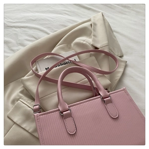 Dettaglio della borsa tote in pelle PU rosa con goffratura a righe verticali su blazer