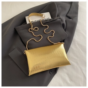 Detail view of golden textured pleated evening clutch bag with fine metal chain strap