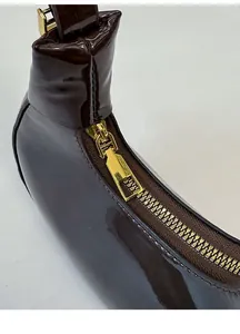 Dettaglio della borsa in vernice cioccolato con cerniera in metallo dorato e fibbia quadrata