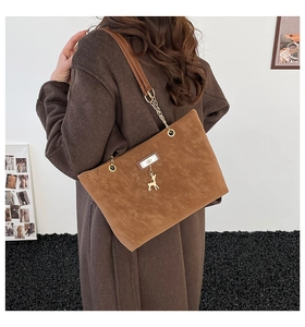 Detail of brown faux suede tote bag with golden deer charm and chain shoulder strap