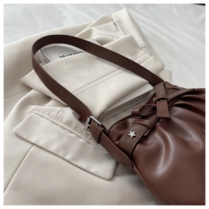 Detail of dark brown pleated tote bag with bow tie, star studs and adjustable strap