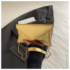 Close-up of golden envelope bag with ripple metal texture and fine chain strap