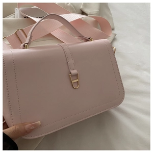 Pink PU leather crossbody bag featuring a golden trapezoidal lock and wide fabric strap