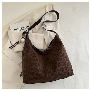 Detail of leopard print hobo bag featuring a creative baseball charm and silver metal hardware