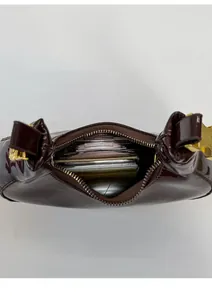Interno spazioso di una borsa in pelle bordeaux lucida con accessori e zip dorata