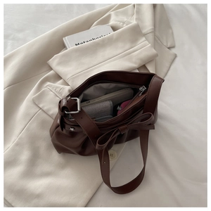 Detail view of large dark brown bow tote bag showing spacious interior and pleated PU leather