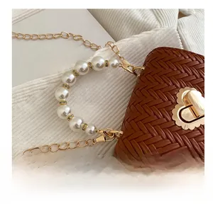 Detailed close-up of woven texture bag with heart lock and white pearl handle