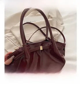 Detailed view of wine red bucket bag with bow ornament and gold hardware accents