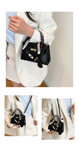 Detail of glossy black crocodile embossed handbag with silk scarf wrapped handle and lock