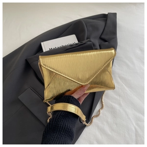 Detailed macro shot of the textured golden pleated fabric and chain strap on the envelope bag