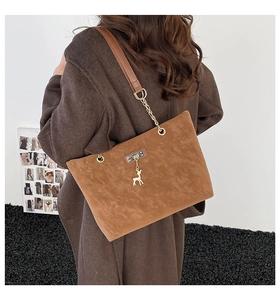 Brown frosted leather tote bag with gold deer charm and chain strap shown on shoulder