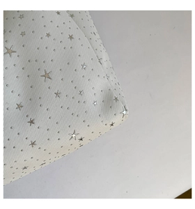 Detailed macro view of white textured fabric with silver star studs and metal rivets