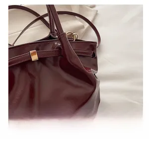 Detailed close-up of glossy wine red leather handbag with shiny metallic buckle