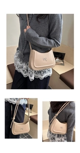 Detail of minimalist beige leather shoulder bag featuring a silver metal bow buckle