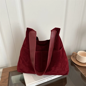 Burgundy matte suede tote bag with long leather handles in a cozy lifestyle setting