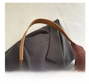 Dettaglio della pelle scamosciata marrone e cuciture del manico in pelle di questa borsa
