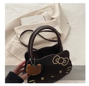 Detailed view of chocolate Hello Kitty shaped handbag with yellow bow and plush bear charm