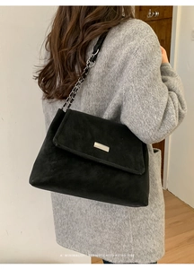 Dettaglio di una borsa in pelle scamosciata nera con catena d'argento e fibbia sottile