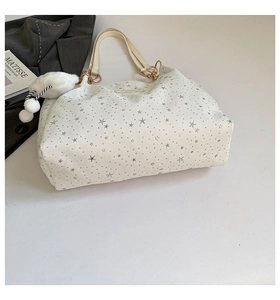 Top view of cream tote bag with silver star patterns, plush cloud charm, and gold hardware