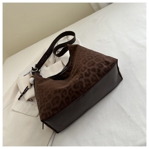 Detail of leopard print shoulder bag with brown leather base and baseball bat charm