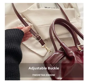 Detailed close-up of golden adjustable buckle and lobster clasp on burgundy leather bag