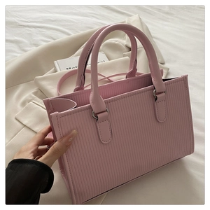Dettaglio della borsa rosa a pieghe su lenzuolo bianco con una giacca chiara