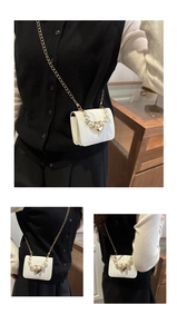 Close-up of white woven crossbody bag with pearl handle and golden triangle lock