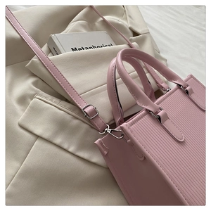 Dettaglio della trama in pelle plissettata rosa chiaro di una borsa a tracolla quadrata