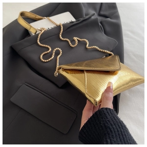 Close-up of golden envelope bag with water ripple texture and metallic bead chain