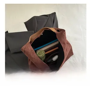 Vista macro dell'interno della spaziosa borsa tote in pelle scamosciata con ombrello e libri