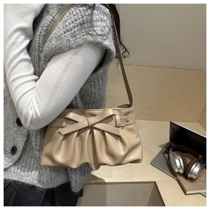 Dettaglio della borsa tote beige a pieghe con grande fiocco e borchie a stella