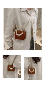 Close-up of brown woven mini square bag with pearl accents and gold heart clasp