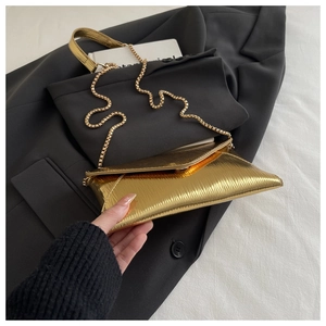 Detailed macro of gold pleated envelope bag with elegant metallic chain strap and texture