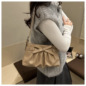 Dettaglio borsa a spalla plissettata beige con fiocco in pelle e borchie a stella