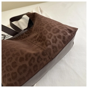 Close-up of leopard print tote bag showing plush texture and brown leather stitching