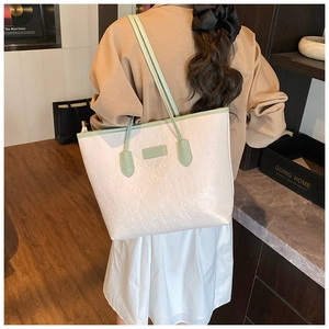 Close-up of heart and cat-paw embossed patterns on beige tote with green trim straps