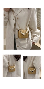 Detail of yellow woven mini bag with pearl handle, heart lock and gold chain strap