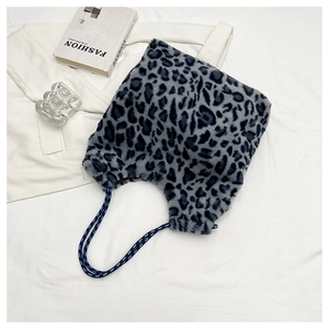 Détail du sac cabas en peluche léopard avec des poignées tissées bleues sur tissu blanc