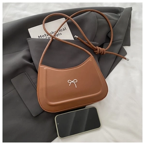 Detailed view of brown leather crescent bag with silver bow and knotted shoulder strap
