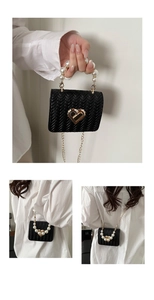 Detail of black woven mini bag featuring pearl handle and golden heart clasp lock