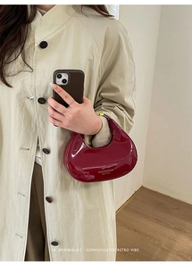 Dettaglio della borsa a mezzaluna in vernice bordeaux con zip in metallo e marchio