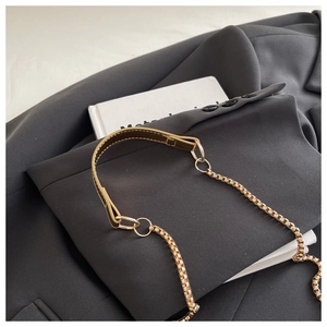 Detailed shot of premium golden box chain and coffee brown leather strap on a blazer