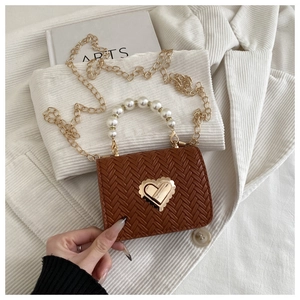 Detail of brown woven mini bag featuring pearl handle and gold heart lock closure