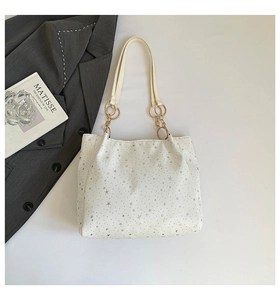 Detail of white canvas tote with silver stars and gold chain leather handle