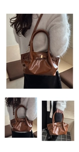 Detailed view of dark brown glossy tote bag featuring unique pleated design and metal buckle