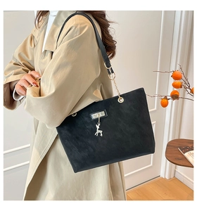 Fashionable black matte leather tote bag with deer charm shown on shoulder for daily commute