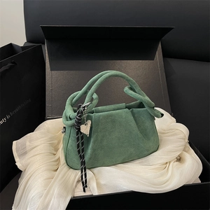 Deep green suede handbag with pleated cloud design and silver heart pendant on white satin