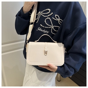 Detail of off-white crossbody bag with wide strap and gold horseshoe buckle